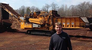 Connecticut Mulch distributors in front of their CBI wood grinder that they use for mulch.