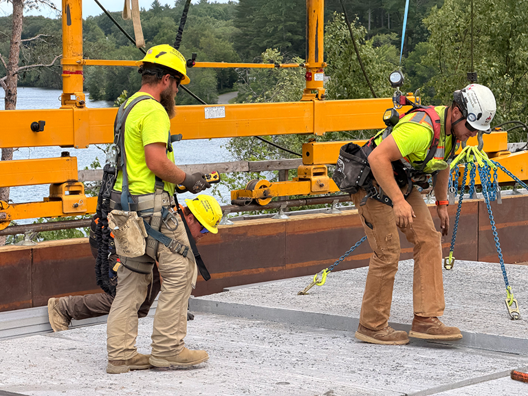 Two Construction Workers Placing Concrete Slabs On A Bridge