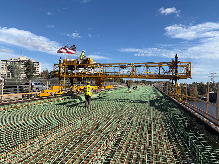 Construction Workers Transporting Rebar Along A Bridge Under Construction