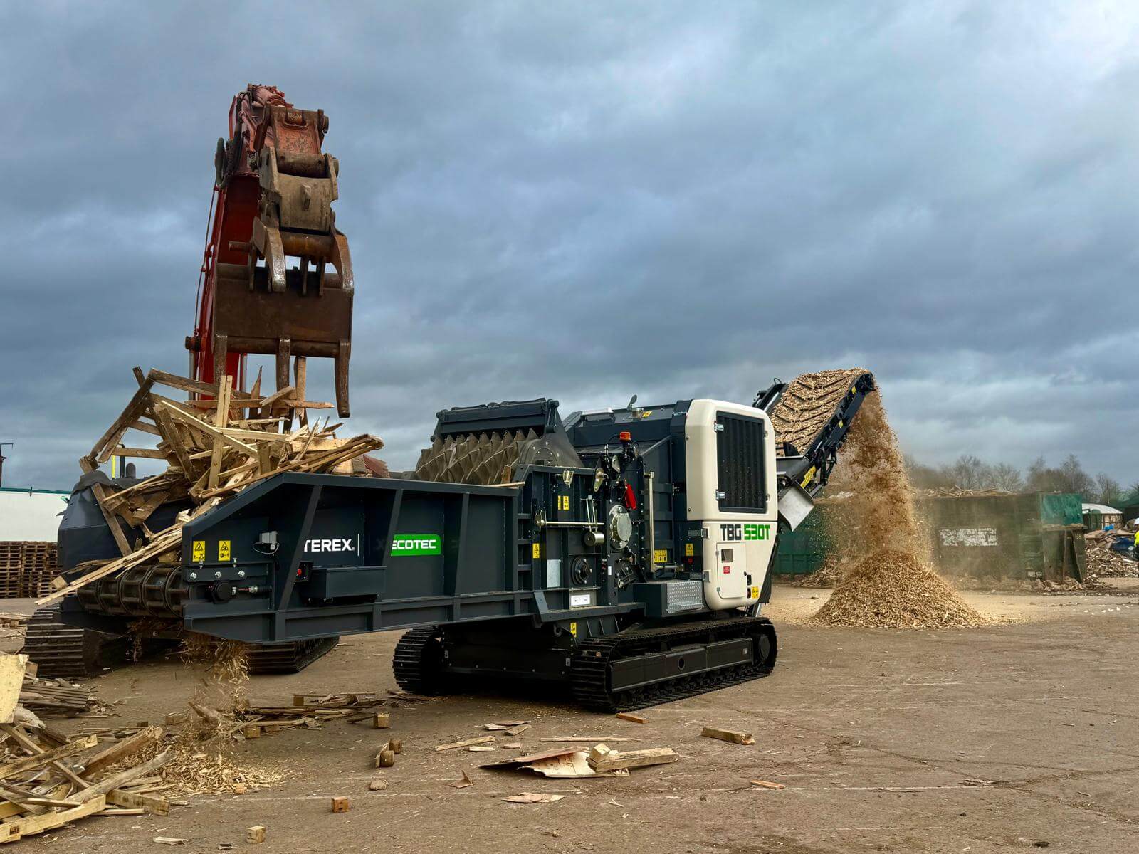 Grab Machine Feeding Scarp Woood Waste Into Ecotec Shredder