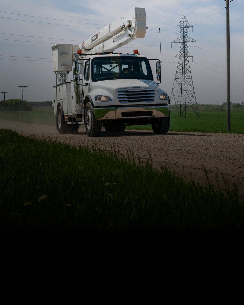 Terex bucket truck driving down gravel road