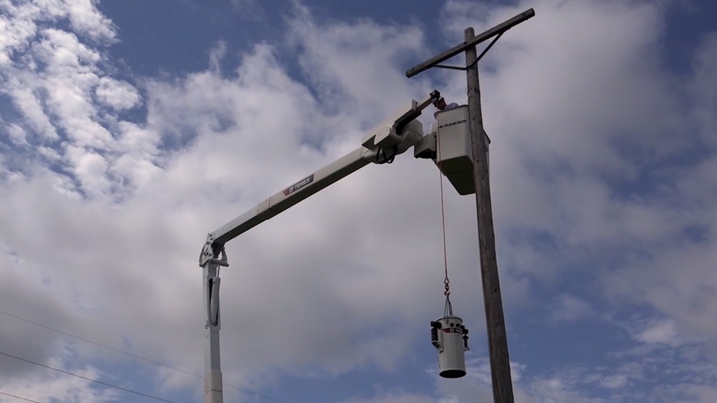 Utility worker lifting transformer in Terex bucket truck