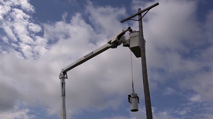 Utility worker lifting transformer in Terex bucket truck
