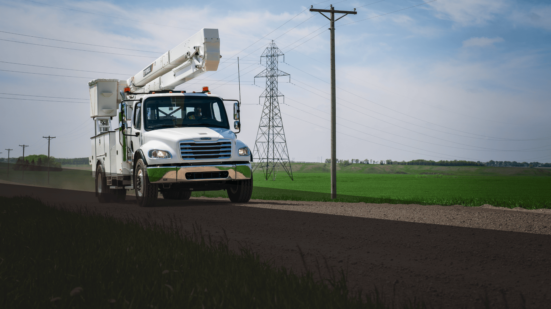 Terex bucket truck driving down gravel road