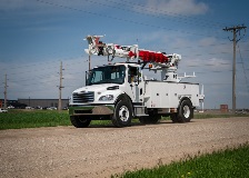 Terex digger derrick driving on a gravel road.