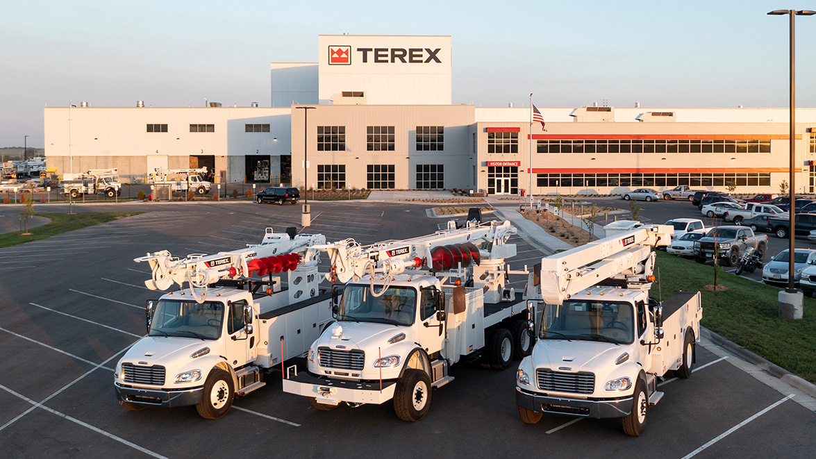 Terex bucket trucks and digger derricks parked in front of factory
